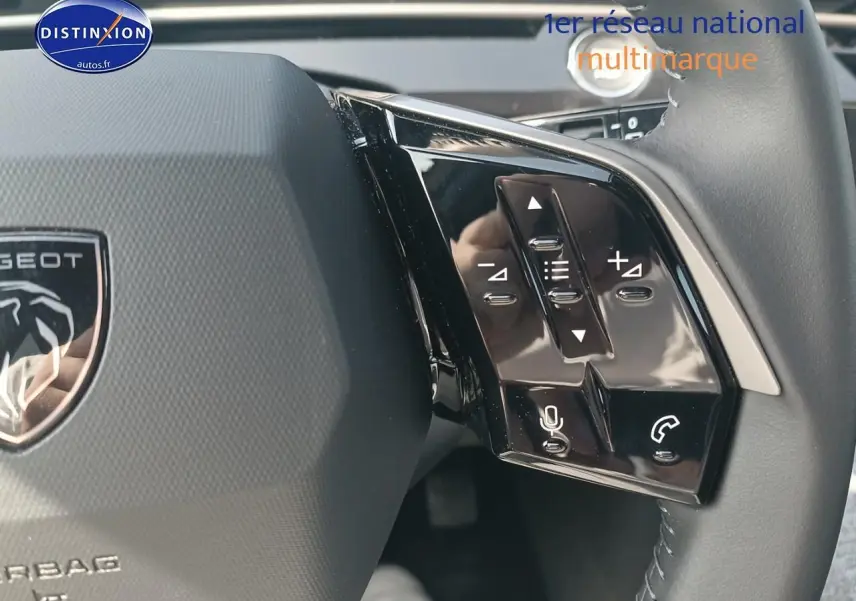 Gros plan sur le volant cuir multifonction du Peugeot 5008 gris Artense, avec commandes vocales et audio intégrées.