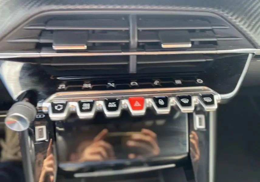 Vue rapprochée de la console centrale du Peugeot 2008, boutons de commande et écran tactile noir brillant.