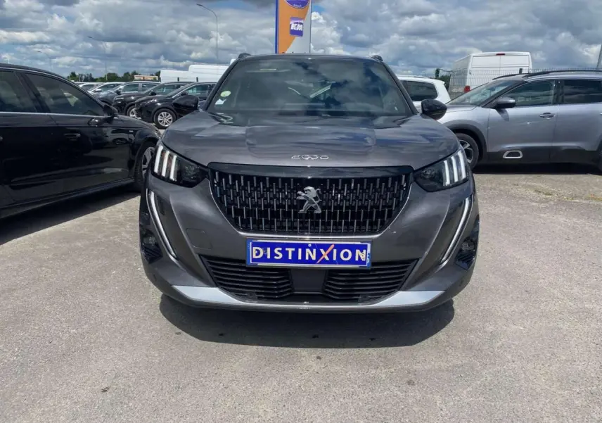 Vue avant du Peugeot 2008 gris foncé avec calandre noire et feux LED à signature 3 griffes, sur parking extérieur.