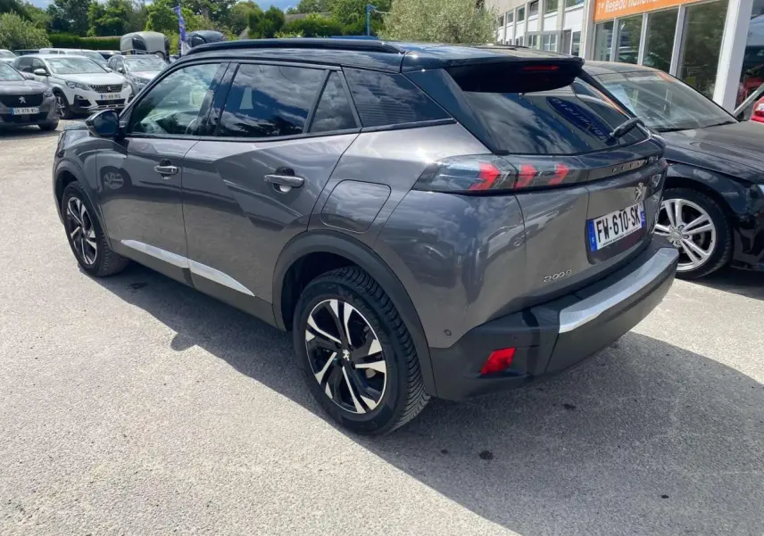 Vue 3/4 arrière droite d'un Peugeot 2008 gris foncé avec jantes alliage bicolores et toit noir brillant.