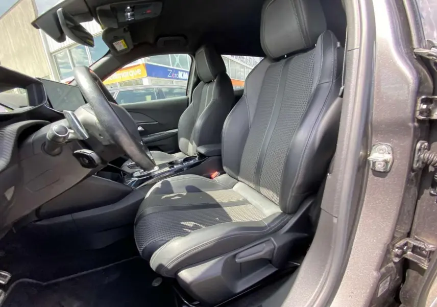 Vue intérieure côté conducteur du Peugeot 2008 2021, sièges en tissu et cuir noir avec surpiqûres grises.