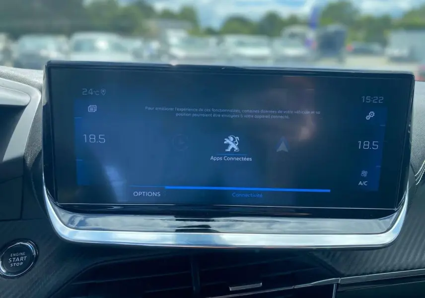 Vue rapprochée de l’écran tactile central du Peugeot 2008 gris foncé, affichant les options de connectivité et la climatisation.