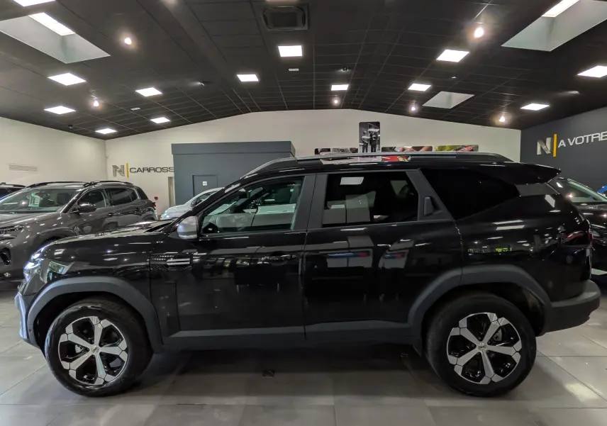 Vue de profil côté gauche du Dacia Bigster noir nacré 2026 en showroom, soulignant ses jantes bi-ton et son design SUV robuste.