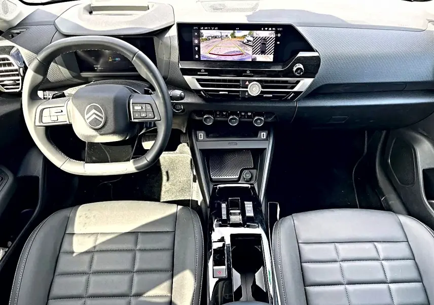 Vue intérieure avant du Citroën C4 X hybride noir 2025, avec tableau de bord moderne et écran tactile affichant la caméra de recul.