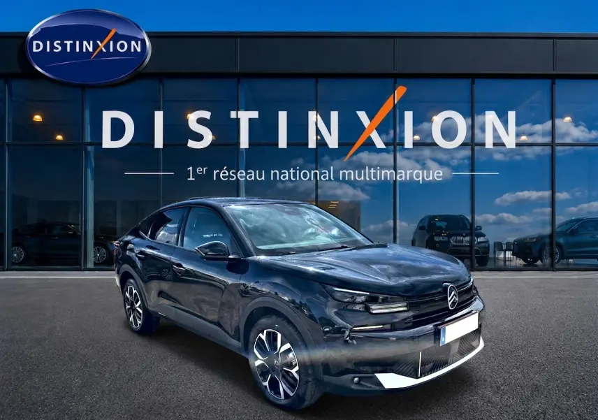 Citroën C4 X noire vue 3/4 avant droit, avec jantes alu et calandre distinctive devant showroom Distinxion.
