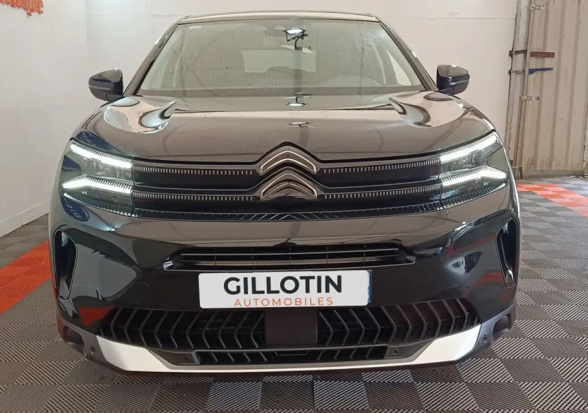 Vue frontale du Citroën C5 Aircross noir 2024 avec calandre distinctive et feux LED allumés en intérieur showroom.
