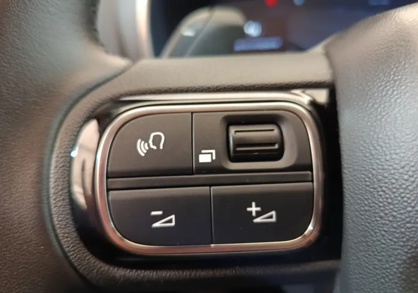 Gros plan sur les commandes vocales et volume au volant cuir du Citroën C5 Aircross 2024 noir, intérieur moderne.
