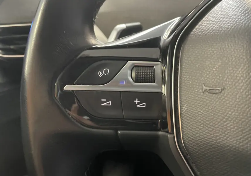 Gros plan sur les commandes de volume au volant noir du Peugeot 5008 blanc nacré, version 1.5 BlueHDi 130 Allure EAT8 de 2019.