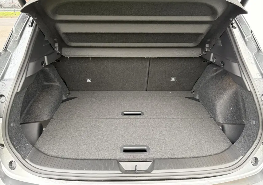 Coffre ouvert du Nissan Qashqai III 1.5 Hybrid e-Power gris foncé, montrant un espace de chargement plat et propre.