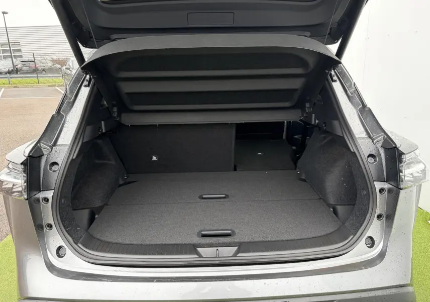 Coffre ouvert vu de l'arrière d'un Nissan Qashqai 2025 gris foncé métallisé avec banquette arrière rabattue.