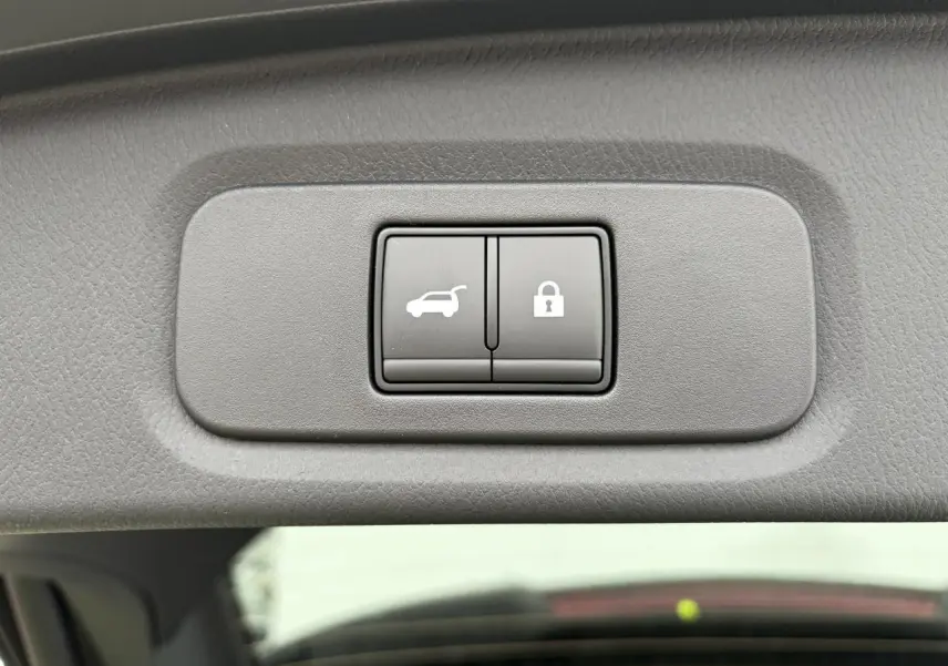 Gros plan sur les boutons d'ouverture électrique et de verrouillage du hayon, intérieur gris du Nissan Qashqai 2025.