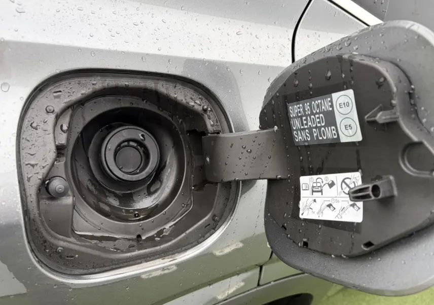 Gros plan sur la trappe à carburant ouverte du Nissan Qashqai gris métallisé sous la pluie.