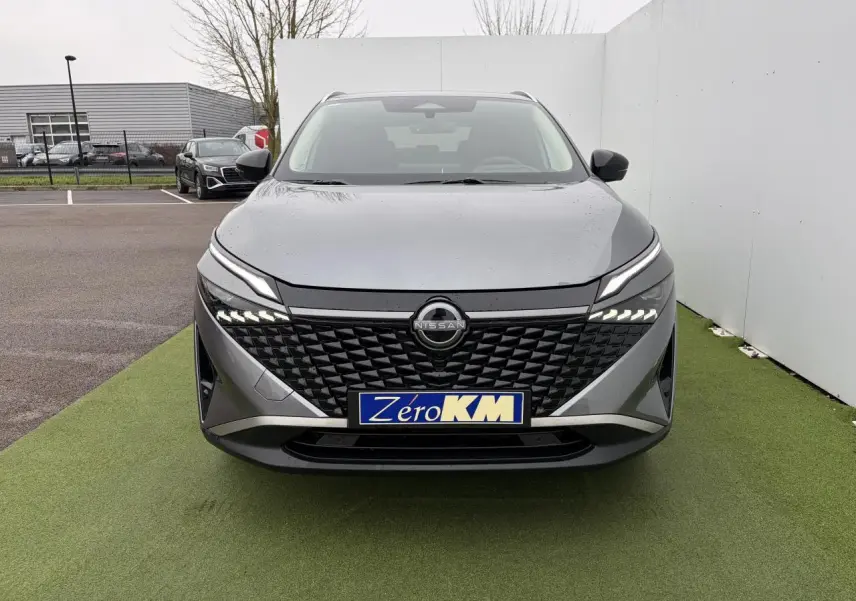 Vue frontale d'un Nissan Qashqai III 1.5 Hybrid E-Power gris foncé avec calandre noire et feux LED distinctifs.