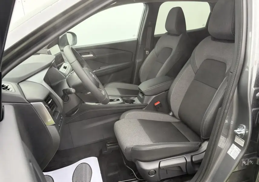 Vue intérieure côté conducteur du Nissan Qashqai 2025 gris foncé, sièges tissu et TEP noir et gris, volant cuir et console centrale.
