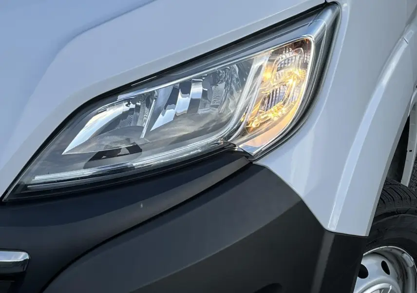 Gros plan sur le phare avant droit du fourgon blanc Opel Movano 2024, mettant en valeur le clignotant allumé.