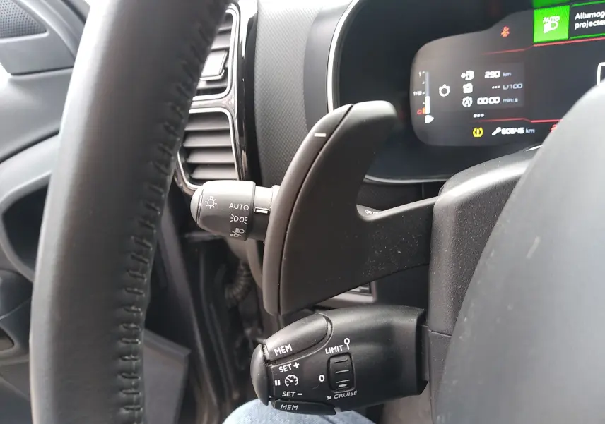 Gros plan sur la commande au volant côté gauche du Citroën C5 Aircross gris platinium, avec affichage numérique en arrière-plan.