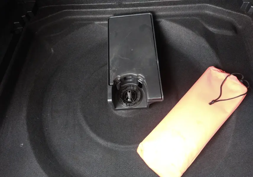 Gros plan sur le coffre du Citroën C5 Aircross 2023 montrant le rangement sous plancher avec trousse de secours orange.