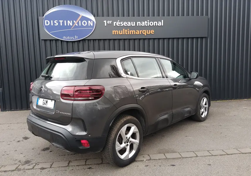 Vue 3/4 arrière droite d'un Citroën C5 Aircross gris platinium avec jantes alliage et protections latérales noires.