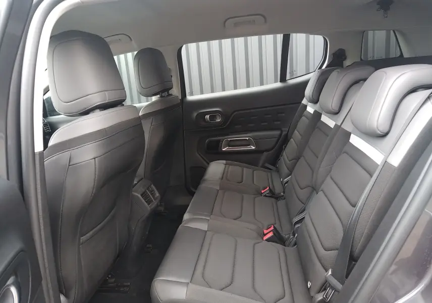 Vue intérieure côté droit des sièges arrière noirs du Citroën C5 Aircross gris platinium, avec appuie-têtes et ceintures visibles.
