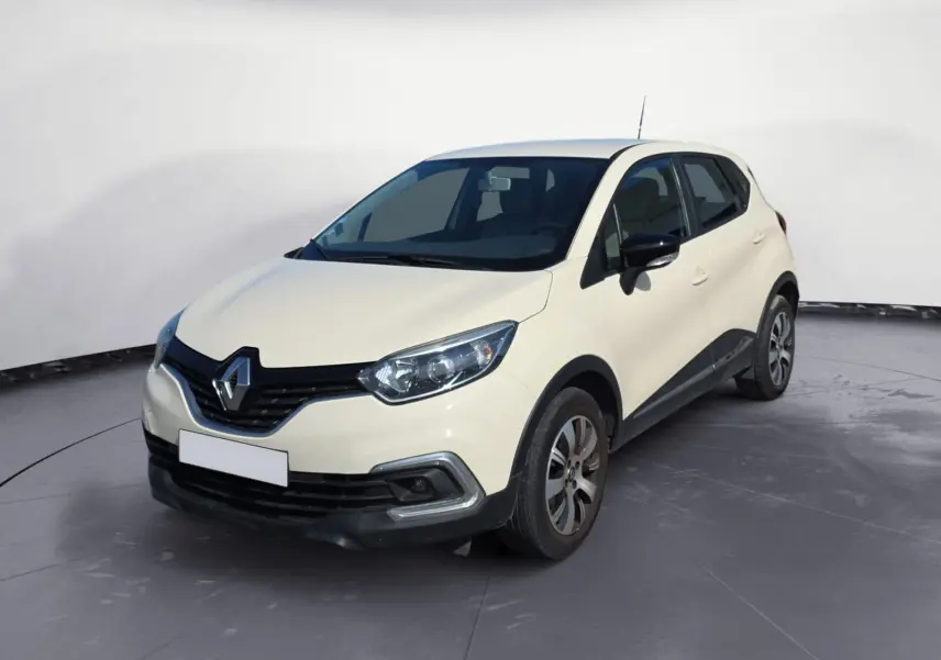 Renault Captur ivoire vue 3/4 avant droit sur parking, avec jantes alliage et calandre noire distinctive.