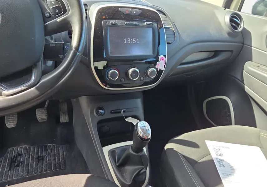 Vue rapprochée de la console centrale noire avec écran tactile et commandes de climatisation du Renault Captur ivoire 2018.