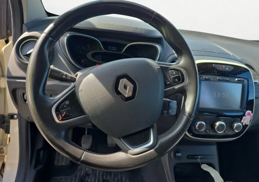 Vue rapprochée du tableau de bord du Renault Captur ivoire 2018, mettant en valeur l'écran GPS et les commandes de climatisation.