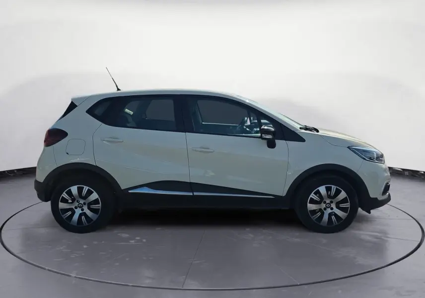 Renault Captur ivoire vue 3/4 arrière droit sur sol gravillonné avec jantes alliage et détails noirs contrastants.