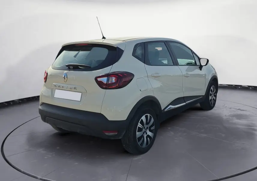 Vue arrière ouverte du coffre d'un Renault Captur ivoire 2018, mettant en valeur l'espace de chargement vide.