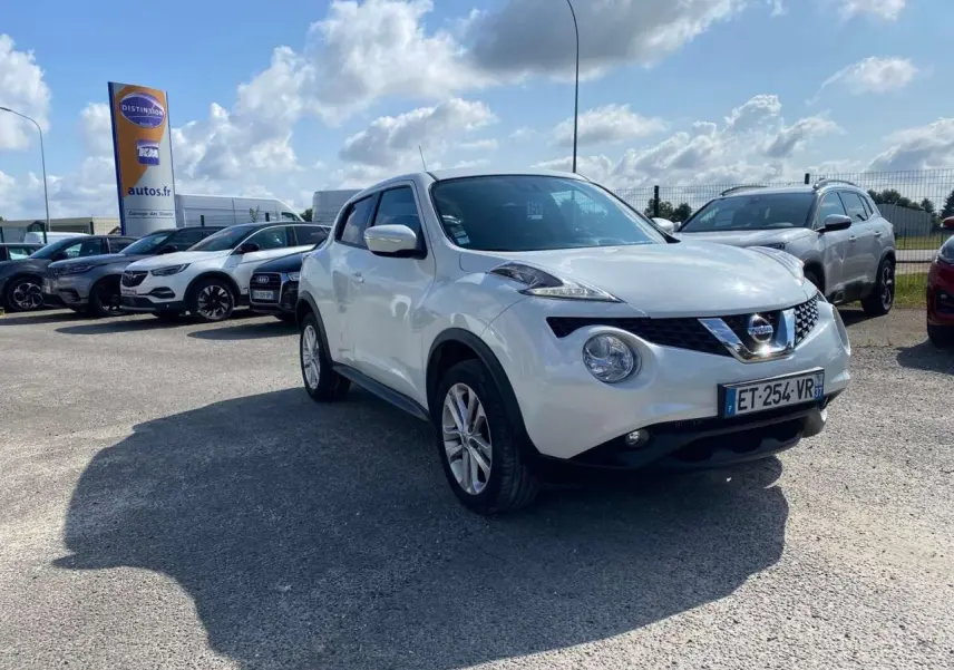 Nissan Juke blanc vue 3/4 avant droit, avec jantes alliage et projecteurs antibrouillard visibles.