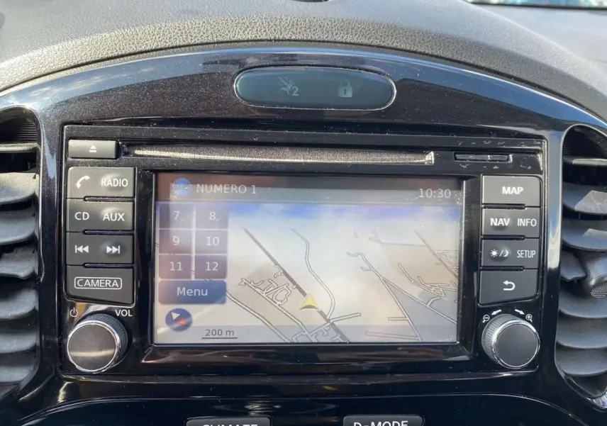 Vue rapprochée de l’écran central du Nissan Juke blanc de 2017, affichant le GPS avec commandes autour.