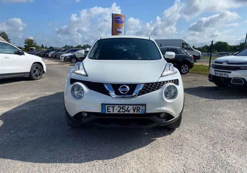 Vue avant d'un Nissan Juke blanc métallisé avec calandre chromée et phares ronds distinctifs.