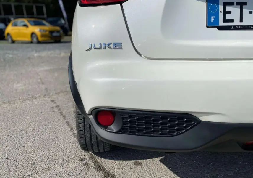 Gros plan sur l’arrière gauche blanc métallisé du Nissan Juke 2017 avec feu antibrouillard et logo visible.