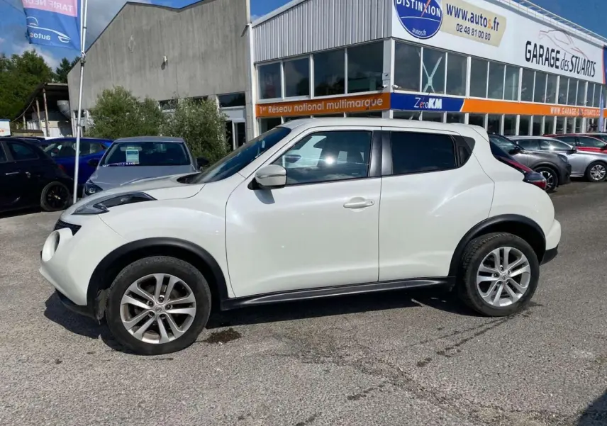 Vue de profil côté gauche d'un Nissan Juke blanc métallisé 2017 avec jantes alliage 17 pouces sur parking extérieur.