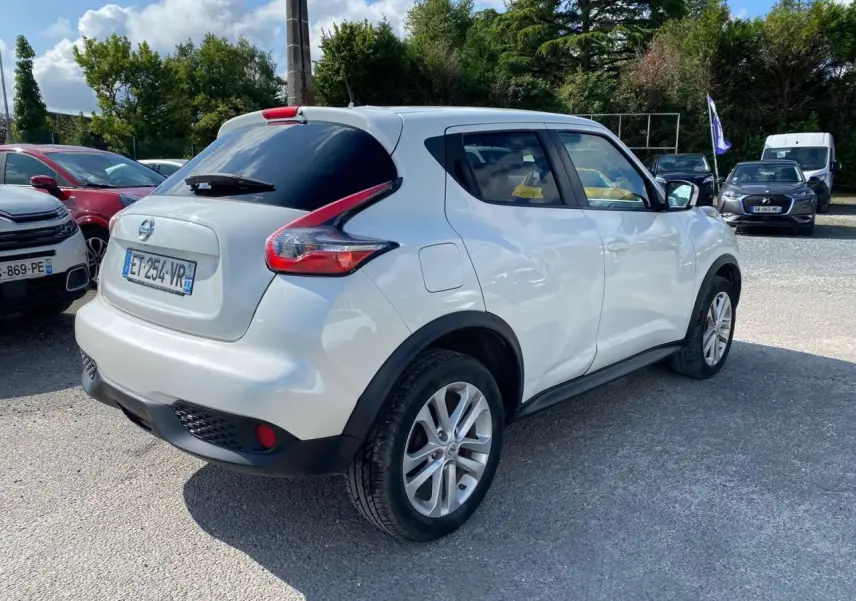 Nissan Juke blanc vue 3/4 arrière droit, vitres arrière surteintées et jantes alliage 17 pouces sport.