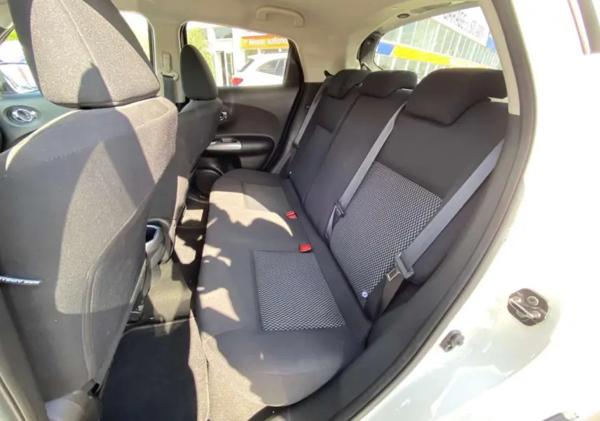 Vue intérieure côté droit sur la banquette arrière noire du Nissan Juke blanc 2017 avec ceinture de sécurité visible.