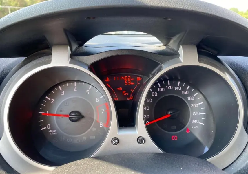 Vue rapprochée du tableau de bord du Nissan Juke blanc, affichant le compteur de vitesse et le compte-tours.