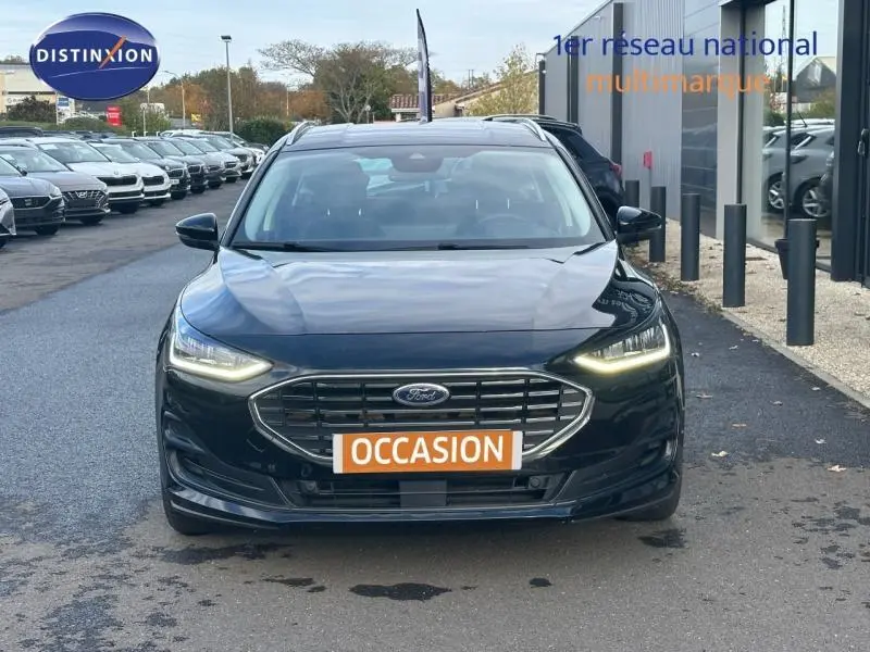 Vue frontale d'une Ford Focus 1.0 Ecoboost Titanium noire avec phares LED allumés et plaque "OCCASION" visible.