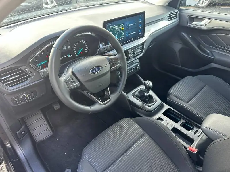 Vue intérieure avant droite de la Ford Focus 1.0 Ecoboost 2023, volant cuir, écran tactile et levier de vitesse manuel.