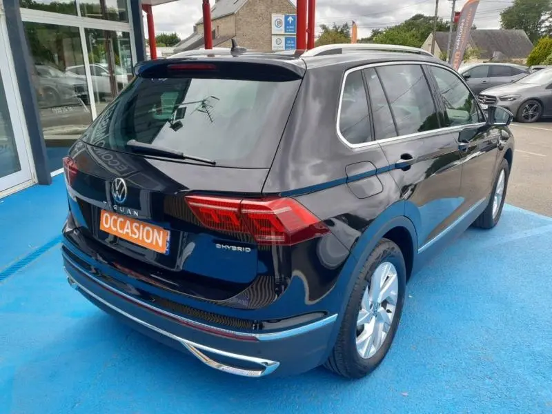 Volkswagen Tiguan 1.4 eHybrid noir nacré, vue 3/4 arrière droit avec jantes alu et barres de toit.