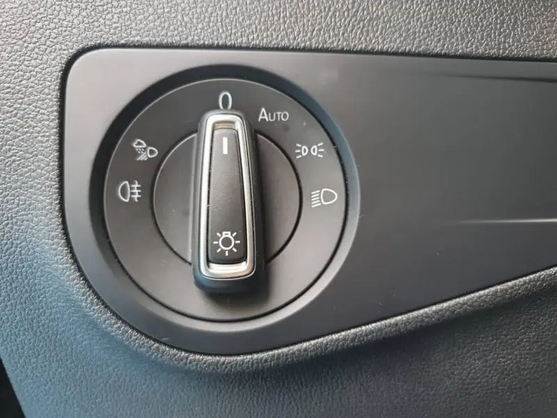Gros plan sur la molette de commande des phares du Volkswagen Tiguan 1.4 eHybrid noir intense nacrée, vue intérieure côté conducteur.