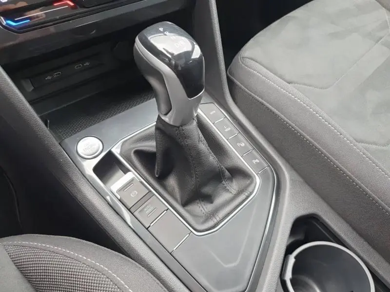 Vue rapprochée de la console centrale du Volkswagen Tiguan 1.4 eHybrid 2022, levier de vitesse automatique et siège tissu gris.