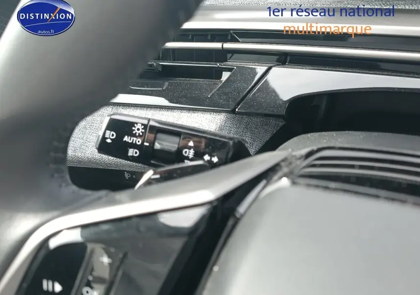Gros plan sur le volant multifonction noir et la commande des phares du tableau de bord du Peugeot 5008 Hybrid 145 allure 2025.