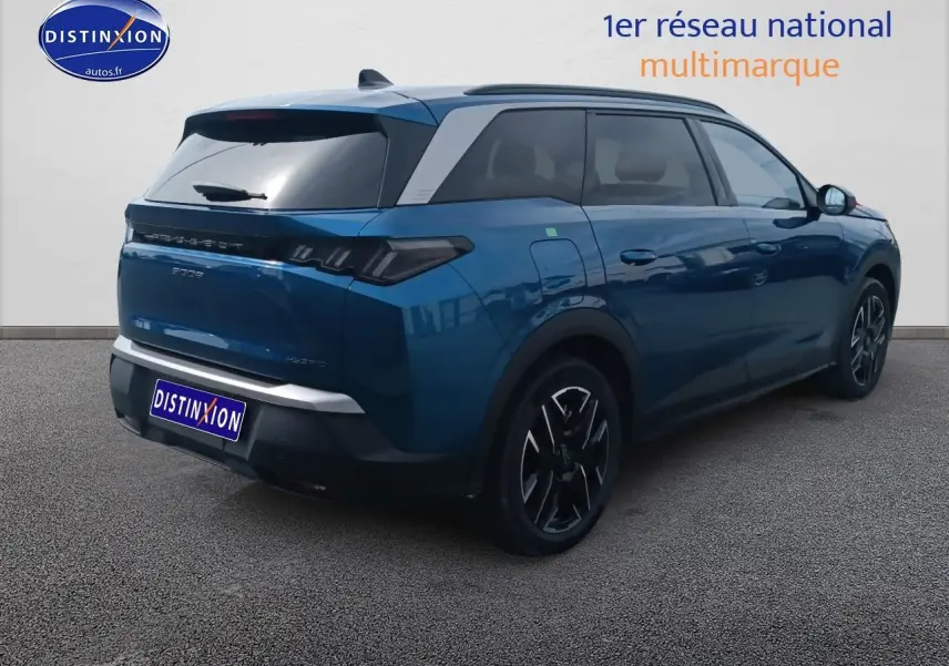 Vue 3/4 arrière droite d’un Peugeot 5008 Hybrid 145 allure e-dcs6 bleu avec jantes alu et toit noir.