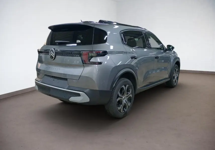 Vue 3/4 arrière droite du Citroën C3 Aircross gris Mercury avec barres de toit noires et vitres surteintées.