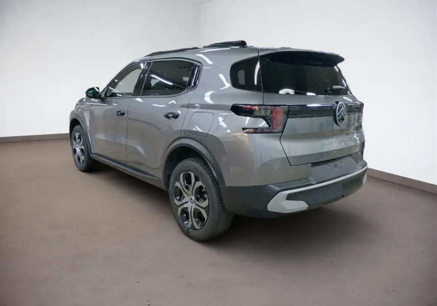 Vue 3/4 arrière droite du Citroën C3 Aircross gris Mercury avec vitres surteintées et barres de toit noires.