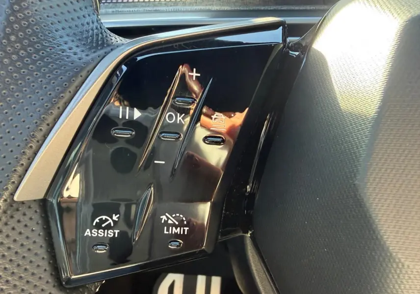 Gros plan sur les commandes au volant noir du Peugeot 5008 Hybrid 145ch GT, côté gauche.