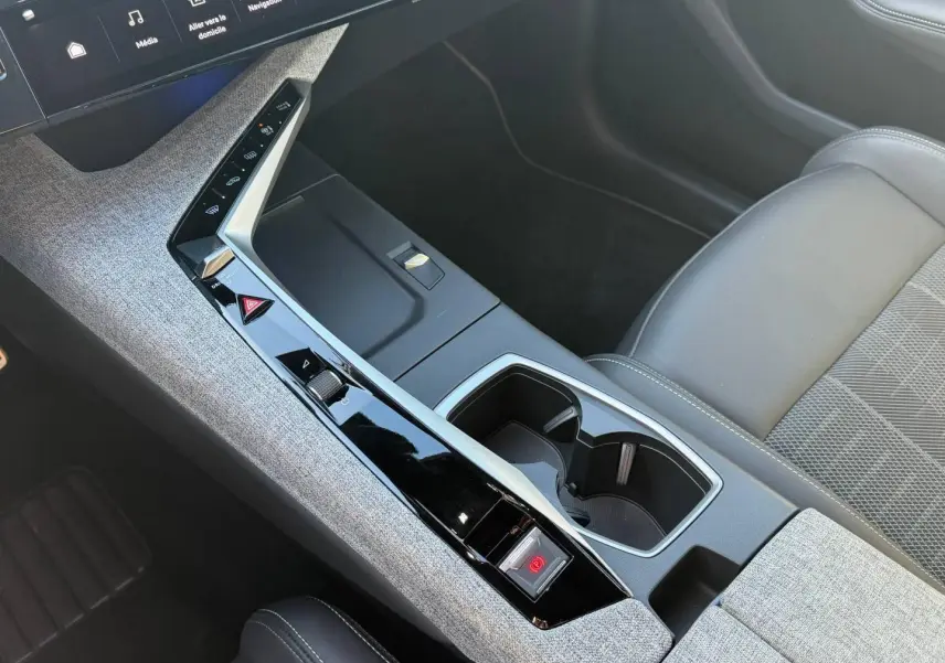 Vue intérieure en plongée sur la console centrale et siège avant droit gris clair du Peugeot 5008 Hybrid 2025.