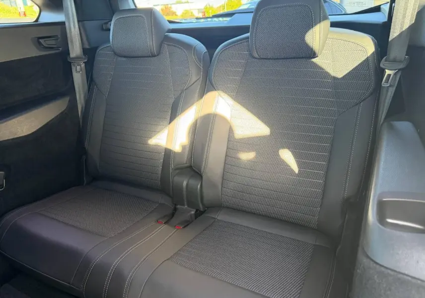 Vue rapprochée des deux sièges arrière noirs en tissu et cuir du Peugeot 5008 Hybrid 2025, avec ceintures visibles.