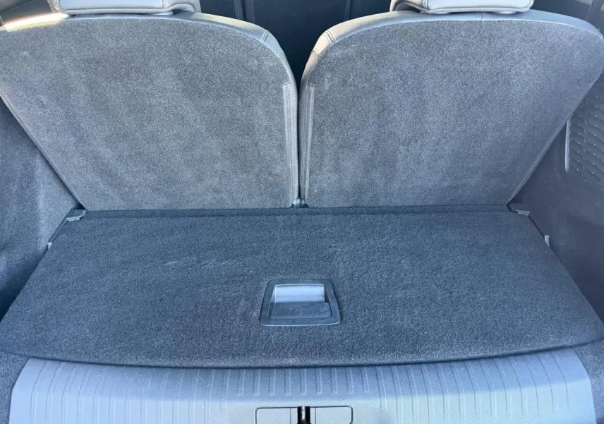 Vue rapprochée du coffre arrière du Peugeot 5008 Hybrid blanc, montrant la banquette arrière rabattue et le plancher de coffre fermé.
