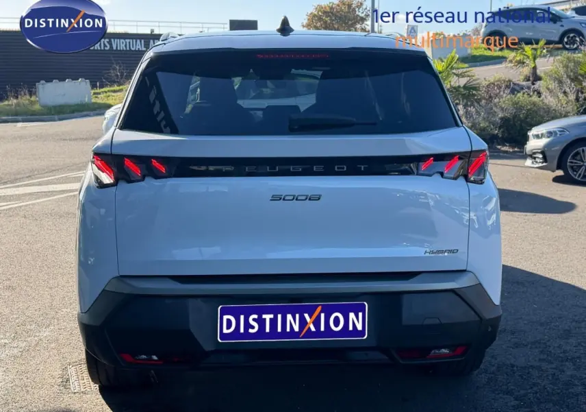 Vue arrière d'un Peugeot 5008 Hybrid blanc Okénite avec feux LED caractéristiques et logo central noir.